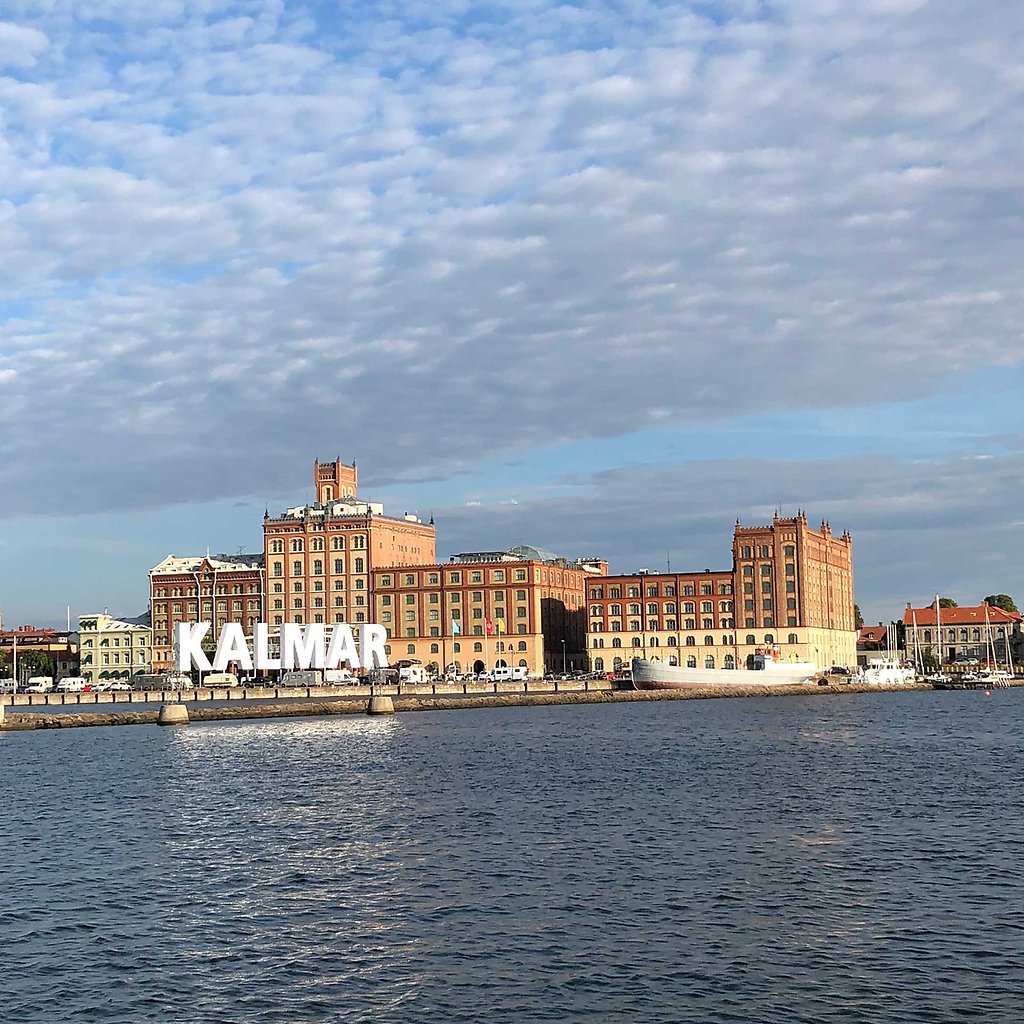 A Kalmar sign in the water and a large red bruick building behind it. 