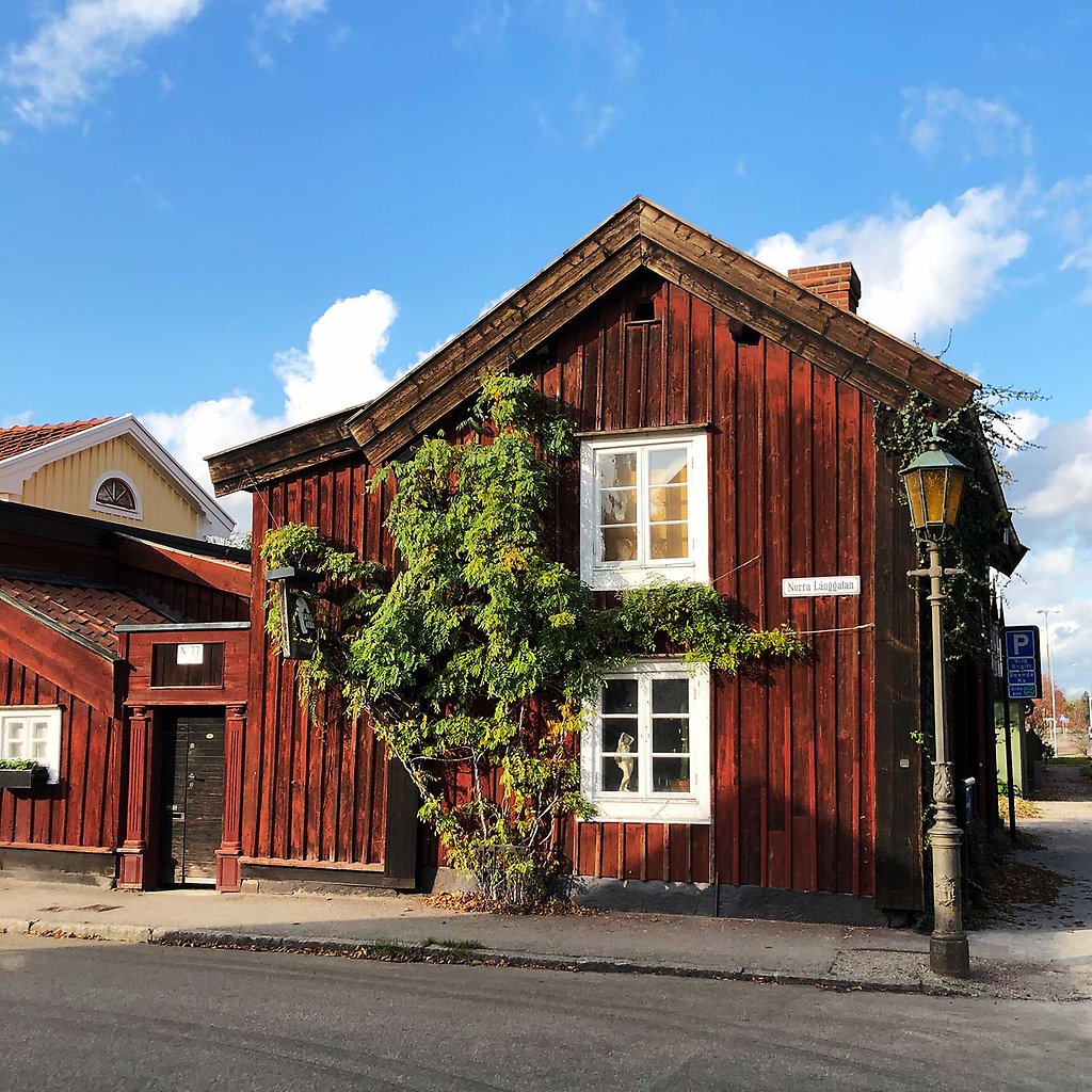 Äldre rött trähus med svarta knutar.